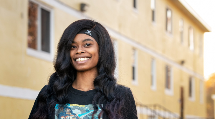 Young black woman with long hair and a black graphic tee smiling